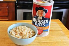 a bowl of oatmeal next to a can of quaker oats on a table