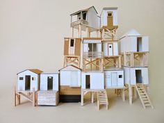 a pile of wooden toy houses sitting on top of a white floor next to each other