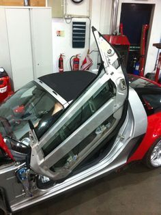 a car being worked on in a garage with its door open and it's hood up