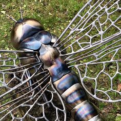 a metal dragon sculpture sitting on top of a lush green field