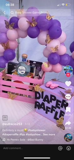 a pink crate filled with lots of purple and gold balloons next to a sign that says diaper raffle