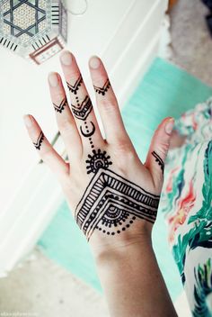 a woman's hand with henna tattoos on it