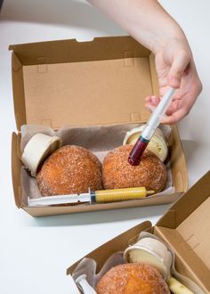 two donuts are in a box with a syringe on top of them