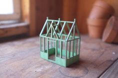 a small green house sitting on top of a wooden table