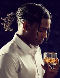 a man with dreadlocks holding a glass of whiskey