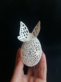 a hand holding a small white object with a butterfly on it's back end