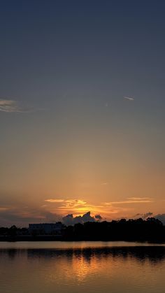 the sun is setting over water with trees in the background