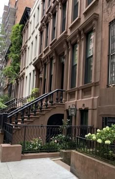 an apartment building with stairs leading up to the front door and flowers growing on the steps