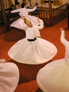 children in white dresses are dancing on the floor