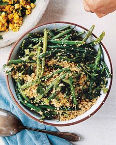 a bowl filled with green beans and other food on top of a white tablecloth