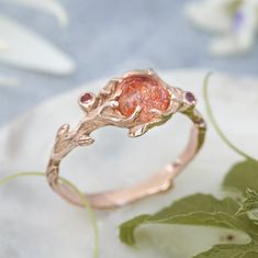 a close up of a ring on a plate with leaves and flowers in the background