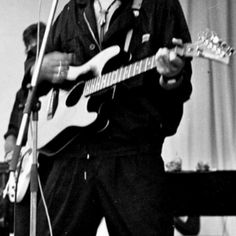 a man standing in front of a microphone and holding a guitar