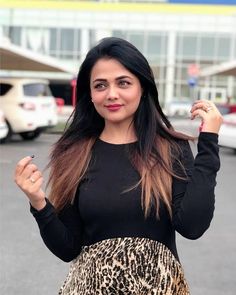 a woman in a black top and leopard print skirt posing for the camera with her hand on her hip