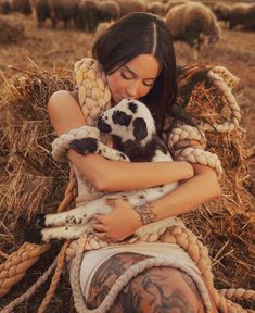 a woman sitting in hay holding a puppy