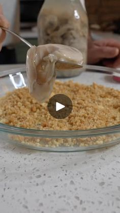 a person is spooning food into a glass bowl on a table with other people in the background