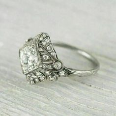 an antique style diamond ring sitting on top of a wooden table