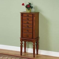 a tall wooden cabinet with drawers and flowers on top in a corner room next to a rug