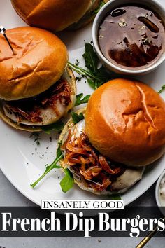 three french dip burgers on a plate with dipping sauce