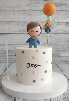 a cake with a person on top that is decorated like an umbrella and some balloons