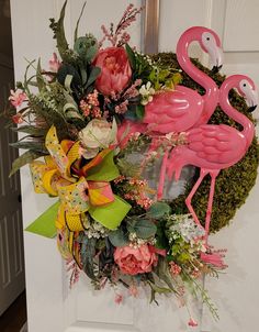 a wreath with pink flamingos and flowers on the front door