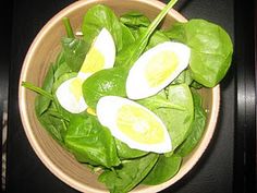 a bowl filled with spinach and hard boiled eggs