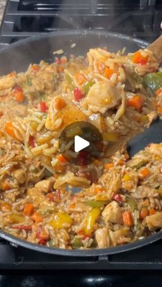 a pan filled with rice and vegetables being stirred by a wooden spoon