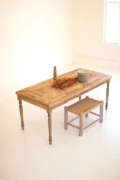 a wooden table sitting in the middle of a room next to a basket and bowl