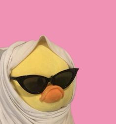 a stuffed penguin wearing sunglasses and a white shawl with black glasses on it's head