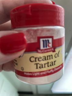 a hand holding a jar of cream of tartar