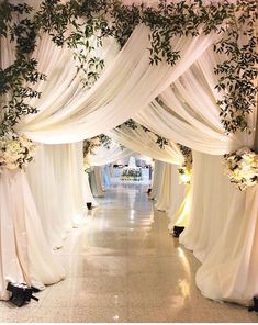 an aisle decorated with white drapes and flowers