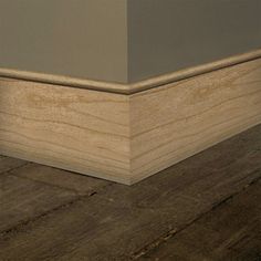 the corner of a room with wood flooring on top of it and an empty wall in the background