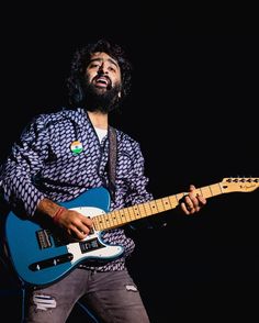 a man with a beard playing an electric guitar