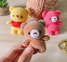 small crocheted teddy bears sitting on a table next to yarn balls and scissors