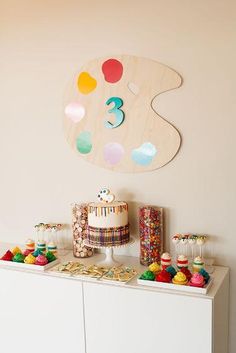 a birthday cake and cupcakes are displayed on a buffet in front of the wall