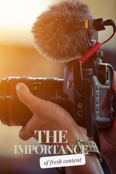 a person holding a camera with a microphone in front of it and the words, the importance of fresh content