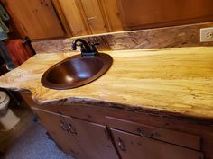 a bathroom sink made out of wood with a brown bowl on the counter top and toilet in the background