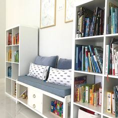 a white book shelf filled with lots of books next to a wall full of books