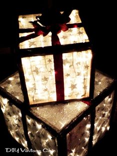 a lit up gift box sitting on top of a glass block with lights around it