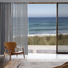 a chair sitting in front of a sliding glass door near an ocean side beach area