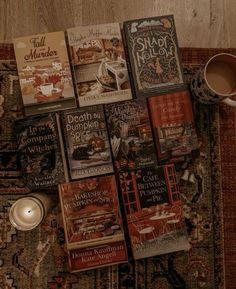 a pile of books sitting on top of a rug next to a cup of coffee