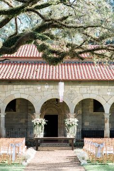 an outdoor ceremony setup with chairs and flowers in front of the entrance to a building