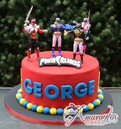 a red cake with toy figures on top and the word george spelled in blue letters