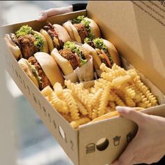 a box filled with lots of different types of food next to a person's hand