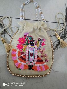 an embroidered bag hanging on a wall with beads and tassels attached to it