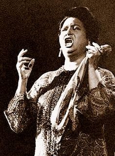 a black and white photo of a woman singing with her hands up in the air