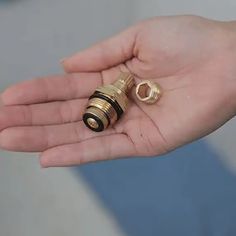 a person is holding two gold colored objects in their hand, one has a ring on it