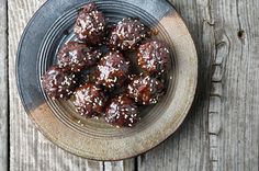 a bowl filled with chocolate covered donuts on top of a wooden table