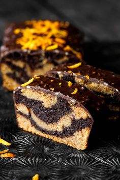 slices of chocolate orange swirl cake on a black plate with yellow zest sprinkles