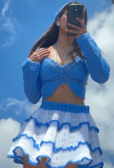 a woman in a blue and white dress taking a selfie with her cell phone