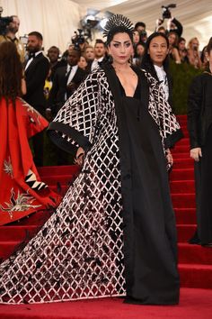 a woman in a black and white gown standing on the red carpet at an event